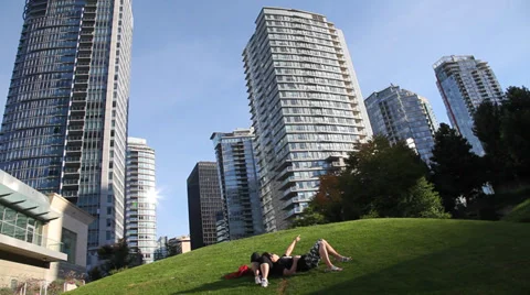 Young couple lying in the sun in front of skyscrapers Stock Footage 30115341