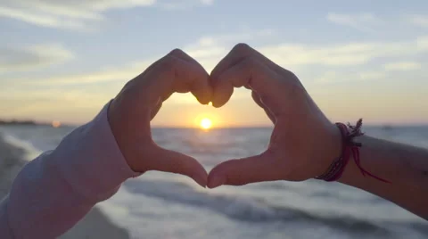 Young Couple Make The Shape Of A Heart Around The Sun At Sunset On The Beach Video stock 55027855