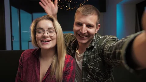 Young couple make video call looking at camera in living room.Man and girl make Stock Footage 225657282