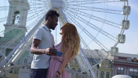 Young couple makes selfie on the background of a ferris wheel Stock Footage 119917976