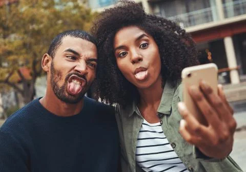 Young couple making funny face while taking selfie on smart phone Stock Photos
