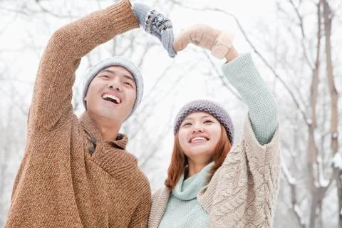 Young couple making heart shape in park in winter Stock Photos