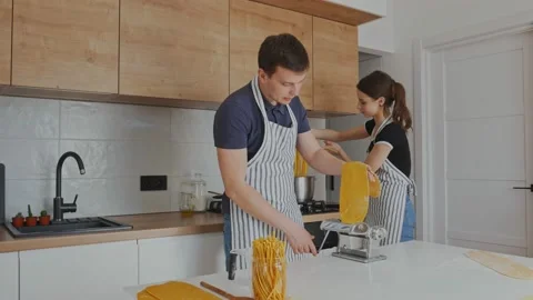 Young couple making home made pasta at kitchen. Family cooking food at home Stock Footage 171472636