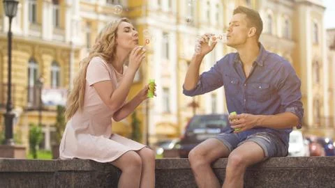 Young couple making soap bubbles, playful romantic mood on date, freedom Stock Photos