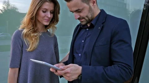Young couple  meets in front of modern building. Man is holding tablet pc. Video stock 55390795