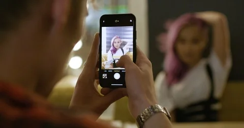 Young couple in a modern caffe, man photographs a girl with pink hair on the Stock Footage 120108821