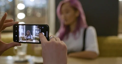 Young couple in a modern caffe, man photographs a girl with pink hair on the Stock Footage 120767944