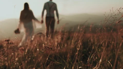 Young couple in the mountains at sunset, in the foreground the grass Stock Footage 139335015