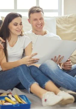Young couple moving in to new home together, sitting on The floor and diskuss Stock Photos