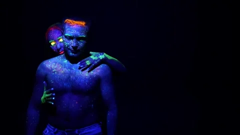 Young couple in neon light with makeup done with fluorescent paints. Stock Footage 313939211