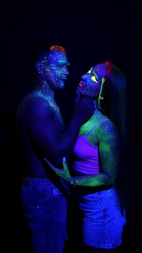 Young couple in neon light with makeup done with fluorescent paints. Stock Footage 314338776