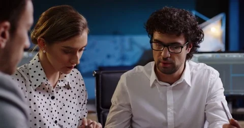 Young couple of office workers consulting about their project while sitting at Stock Footage 82473844
