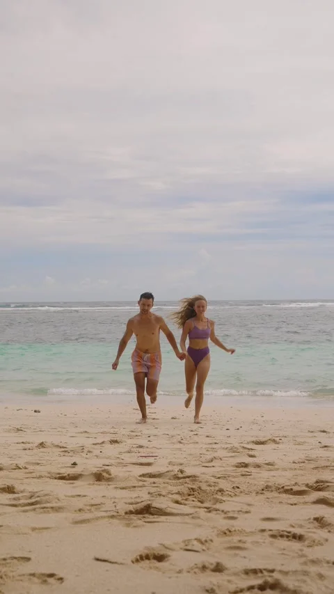 Young couple out of the ocean after swimming, they holding hands Stock Footage 296489170