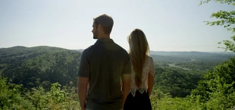 Young Couple Overlooking Cliff, Forest, and Hills, Panning Shot Stock Footage 95638753