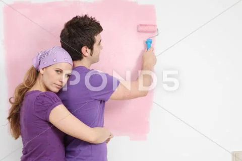 Young couple painting baby nursery in new home Stock Photos