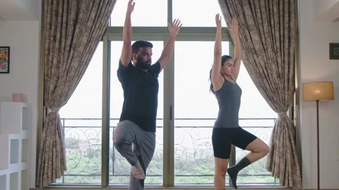 Young couple performing Tree pose Vrikshasana or Utthita Hasta Padangustasana Stock Footage 206635324