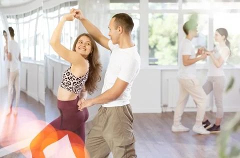 Young couple performs an expressive salsa in bright, modern dance studio during Stock Photos