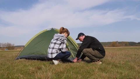 Young couple pitching camping tent together in a meadow 库存影片 319788198