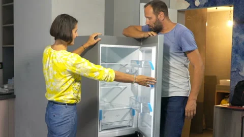 Young couple placing new fridge at new home Stock Footage 106444903