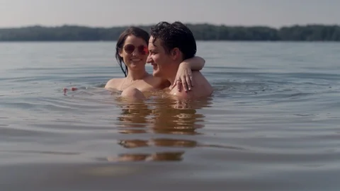 A young couple play around while cooling off in a forest lake in slow motion Stock Footage 116747877