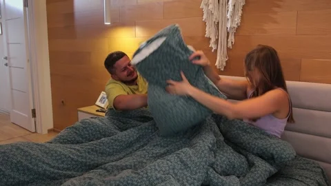 A young couple playfully having a pillow fight on a bed. Stock Footage 290119066