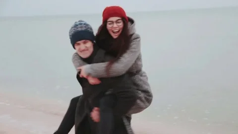 Young couple playing on the beach. Man and girl whirl Stock Footage 70995139