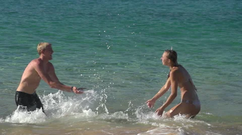 Young couple playing in surf on a beach in Maui 動画素材 43948334