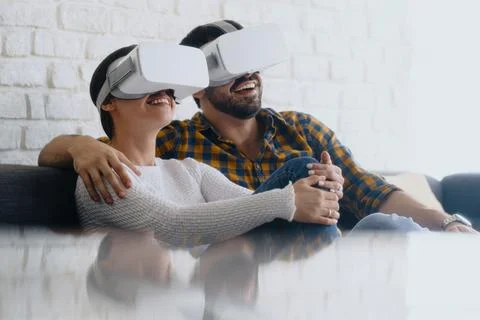Young Couple Playing Virtual Reality With Headset On Sofa Stock Photos