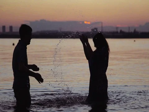Young couple playing in the water at sunset Stock Footage 83531035