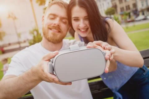A young couple plays a game using virtual reality glasses on the street. Stock Photos