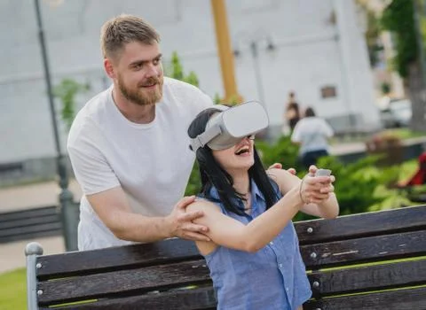 A young couple plays a game using virtual reality glasses on the street. Stock Photos