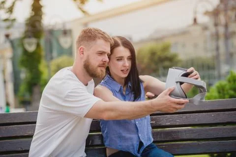 A young couple plays a game using virtual reality glasses on the street. Stock Photos