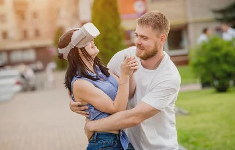 A young couple plays a game using virtual reality glasses on the street. Stock Photos