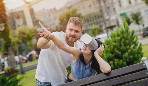 A young couple plays a game using virtual reality glasses on the street. Stock Photos