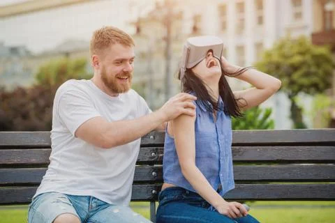 A young couple plays a game using virtual reality glasses on the street. Stock Photos