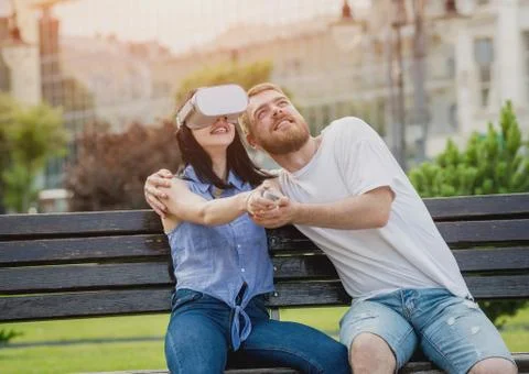 A young couple plays a game using virtual reality glasses on the street. Stock Photos