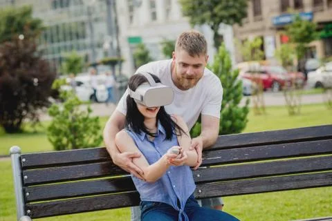 A young couple plays a game using virtual reality glasses on the street. Stock Photos