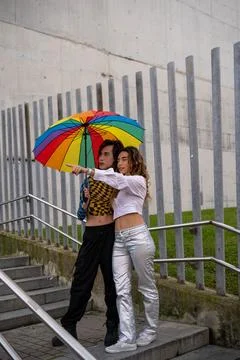 Young couple pointing in a direction under an umbrella. Stock Photos