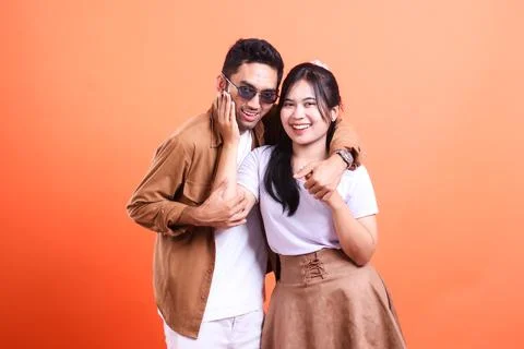 Young couple posing in front of a solid orange background for a portrait shoo Fotos Stock
