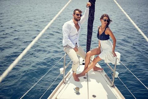 A young couple is posing for a photo and enjoying a photo shooting on a yacht Stock Photos