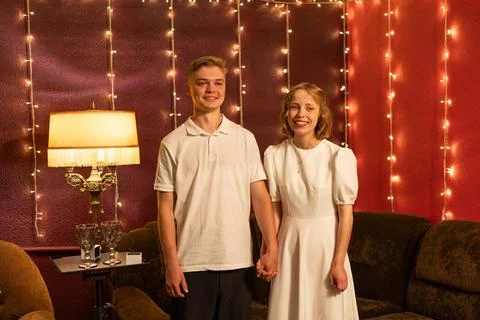 Young couple posing with string lights in a cozy indoor setting Foto stock