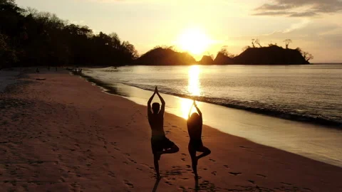 Young couple practicing yoga on the beach at sunset Stock Footage 106938607