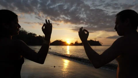 Young couple practicing yoga on the beach at sunset Stock Footage 106939241