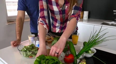 Young couple is preparing dinner.  Man is tasting the sandwich. Close up. Stock Footage 61855585
