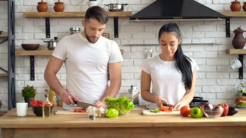 Young couple preparing salad dish together at the kitchen. Talking, smiling. Stock Footage 105121818