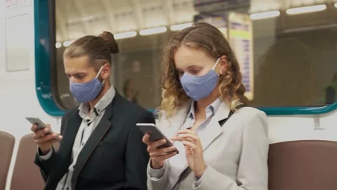 Young couple in protective masks using their smartphones in a subway car. Stock Footage 146443231