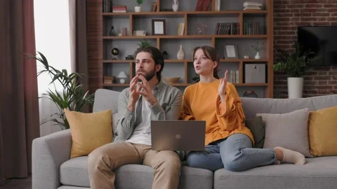 Young couple quarreling while using laptop while sitting on sofa at home. Young 스톡 동영상 197412848