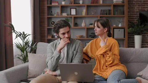 Young couple quarreling while using laptop while sitting on sofa at home. Young Stock Footage 201974025