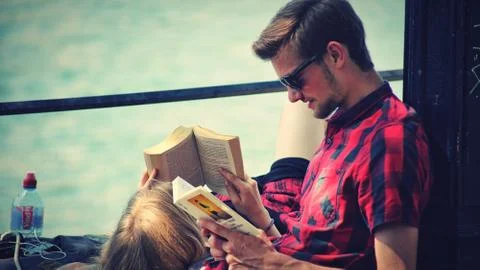 A  young couple reading books by the river Stock Photos