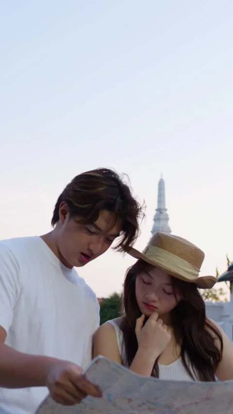 Young couple reading city map at temple at sunset Stock Footage 324847991